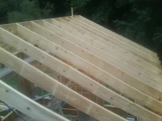 New roof rafters set over an addition before sheathing in Keene