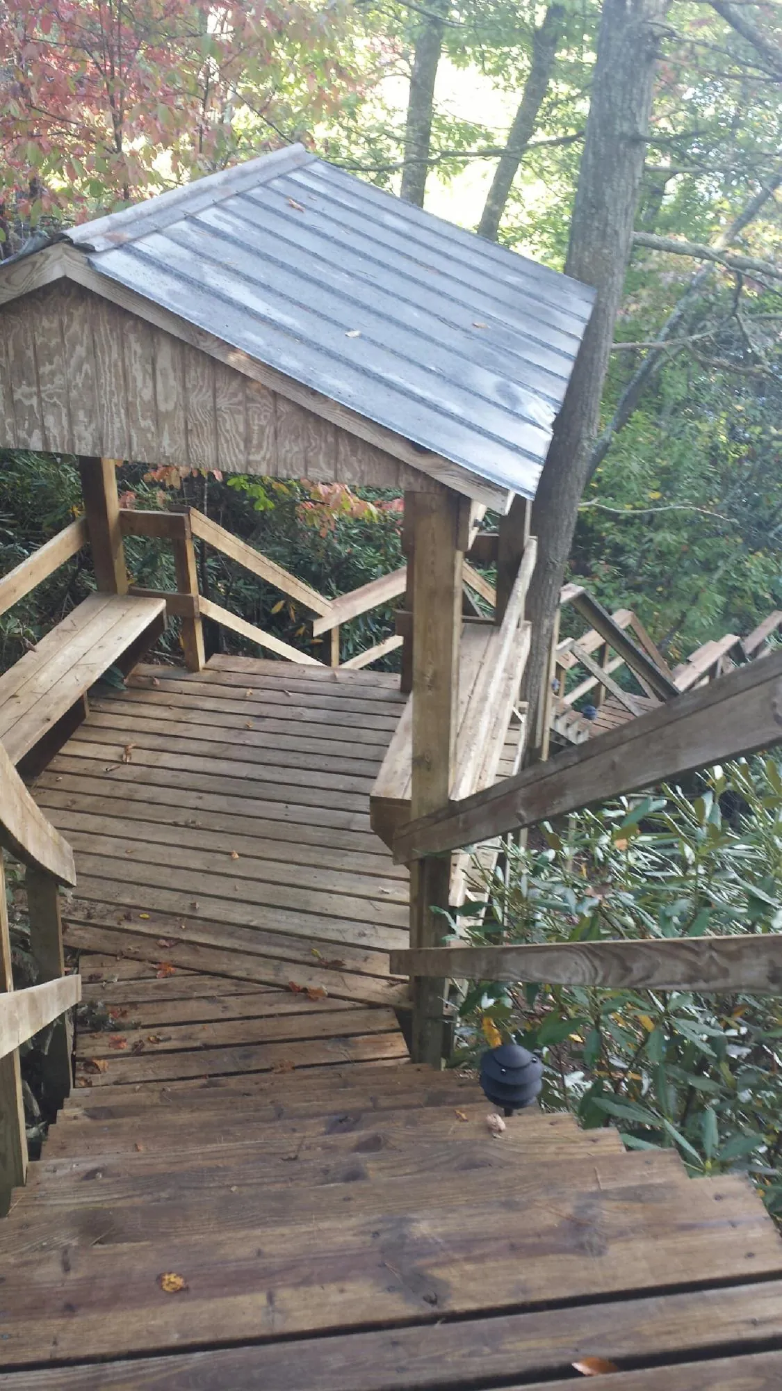 Metal roofed shelter over wooden steps on a wooded walkway — Skylight Repair & Installation work by our crew in Keene