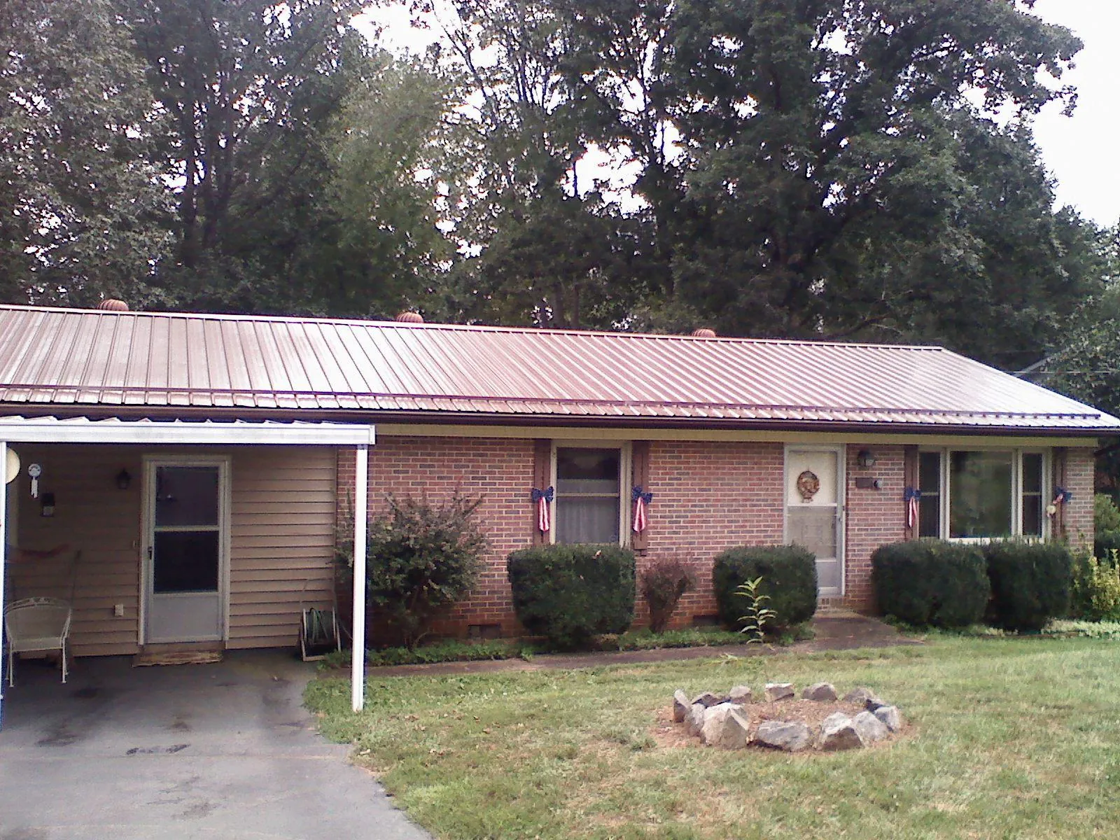 Bronze metal roof and carport on a brick ranch home — Roof Repair work by our crew in Keene